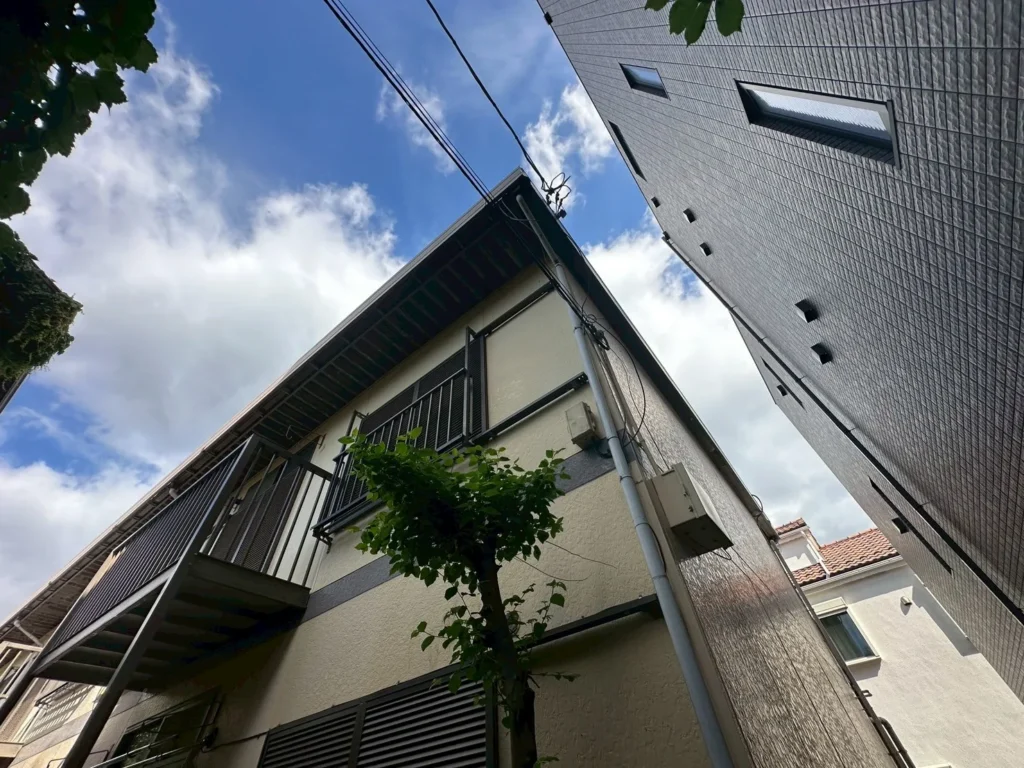下から見上げた2階建て木造アパートの外壁とバルコニー