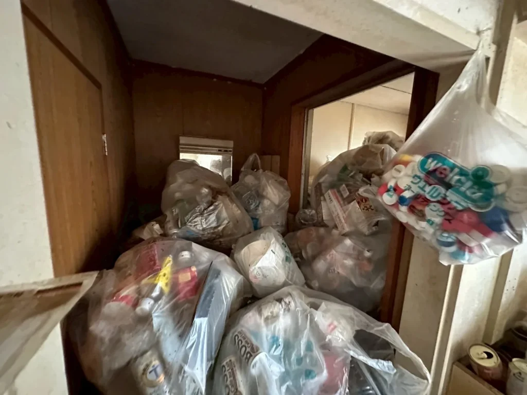 室内の廊下に積み上がったごみ袋などの残置物