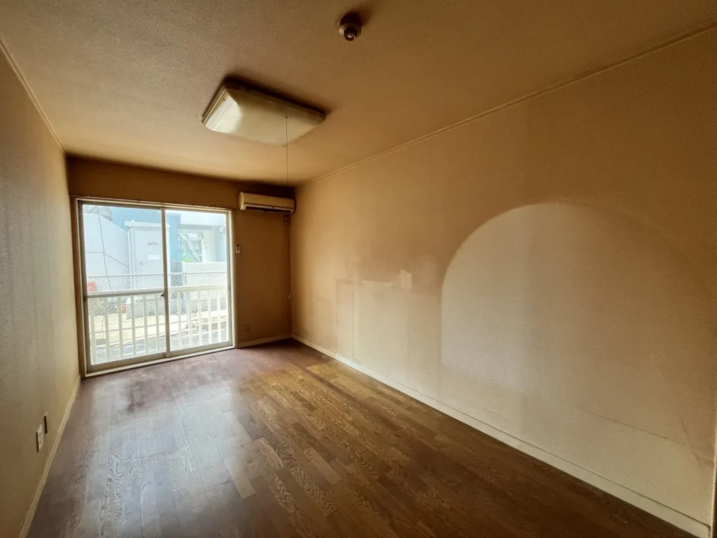 壁に家具の跡としみが残る空室の洋室