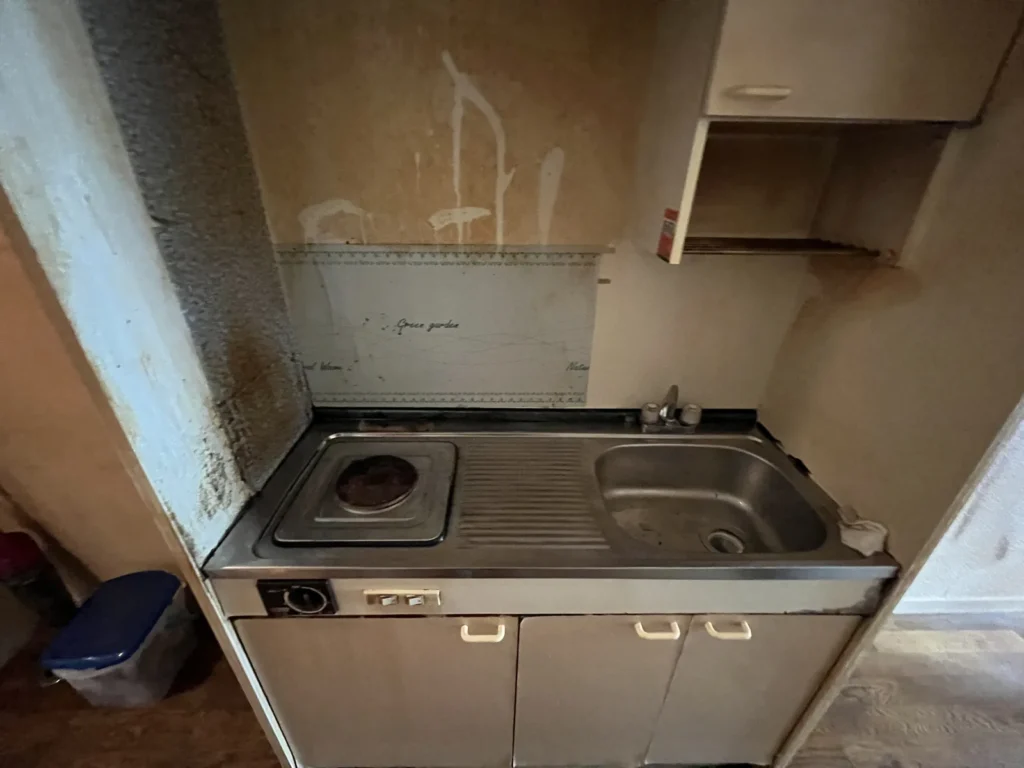 壁が汚れた電気コンロ付きのミニキッチン
