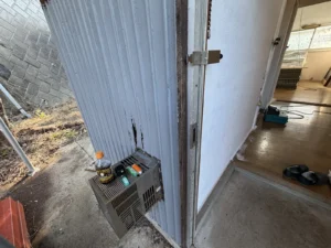 入口脇の外壁トタンに穴とめくれがある玄関まわり