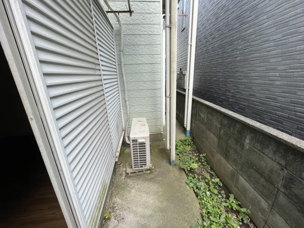 建物裏の通路とエアコン室外機、境界のブロック塀