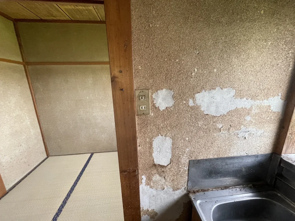 砂壁がはがれて下地が見える台所横の壁