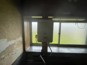 台所の窓前に付いた小型ガス湯沸かし器